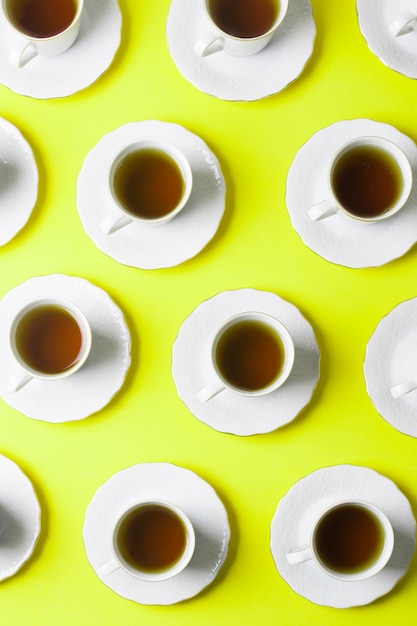 An elevated view of brown herbal tea cups and saucer on neon backdrop