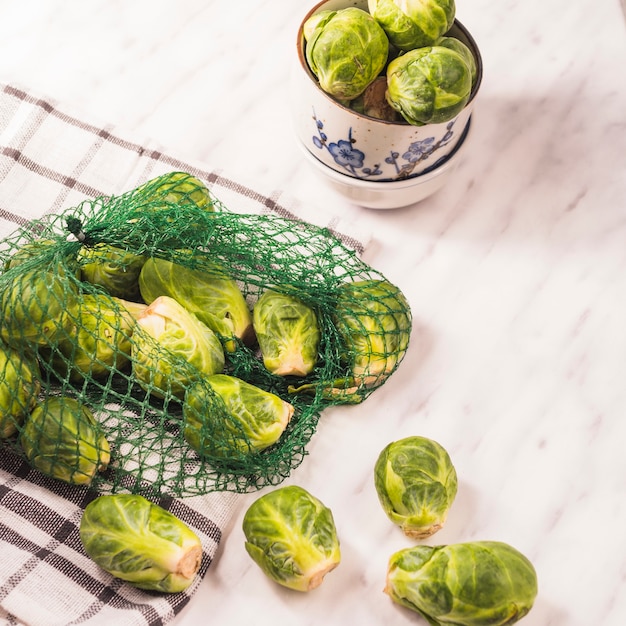 Elevated view of brussels sprouts in net over chequered pattern textile