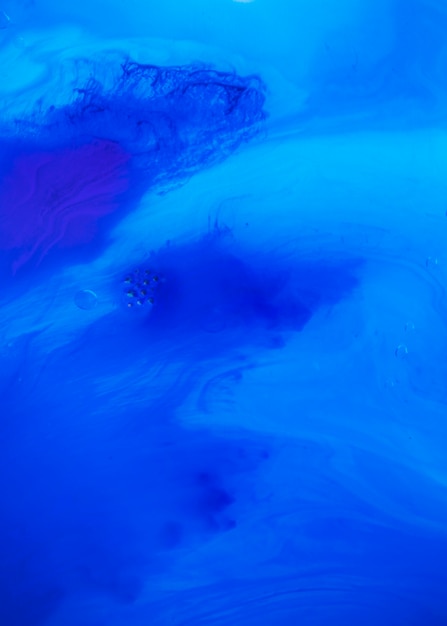 An elevated view of bubbles over the mixing of blue color water paint