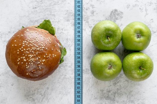 Free photo elevated view of burger and apple compare with measurement tape