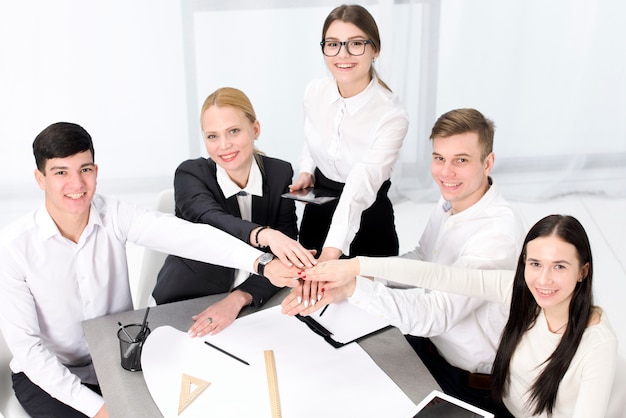 Free photo an elevated view of businessman and businesswoman stacking each other's hand over the project