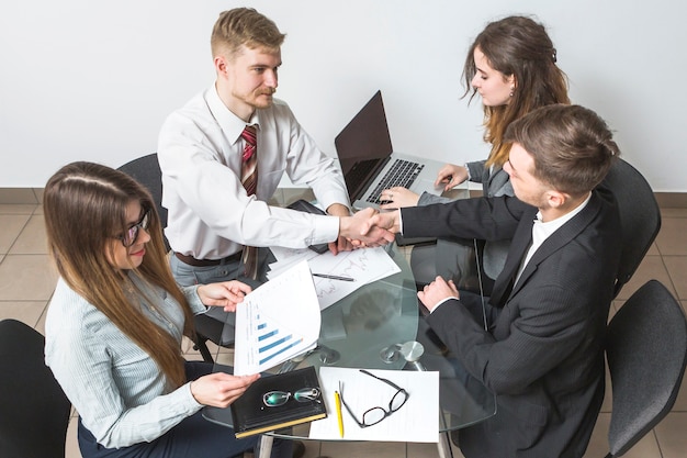 Foto gratuita punto di vista elevato dell'uomo d'affari che agita le mani con il suo partner nel luogo di lavoro