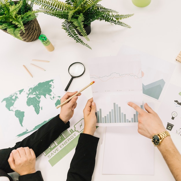 Elevated view of businesspeople analyzing graph over desk