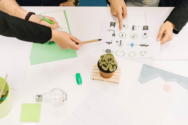 Elevated view of businesspeople hands holding paper with energy saving icons