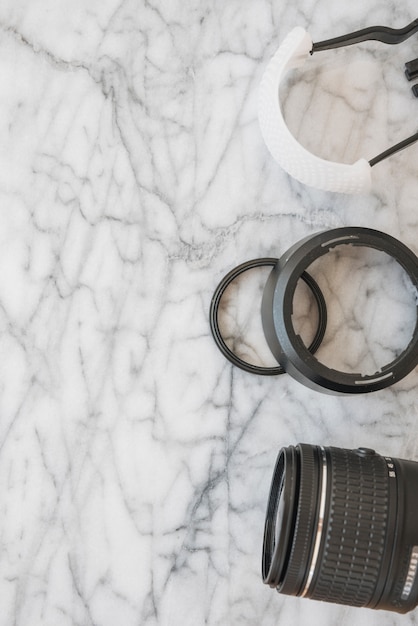 Elevated view of camera lens and accessories on marble textured background
