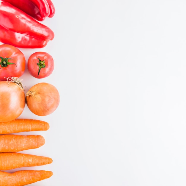 Elevated view of carrots; onions; tomatoes and red bell pepper on white background