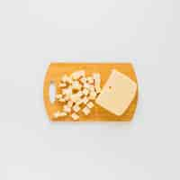 Free photo an elevated view of cheese cubes on wooden chopping board over white background