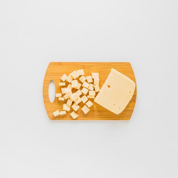 Поднятый вид кубиков сыра на деревянной разделочной доске на белом фоне