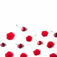 Foto gratuita vista elevata di ciliegia e petali di rosa su sfondo bianco