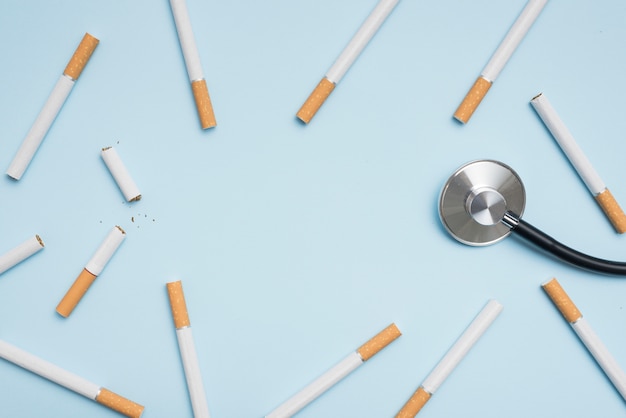 Elevated view of cigarette and stethoscope on blue background