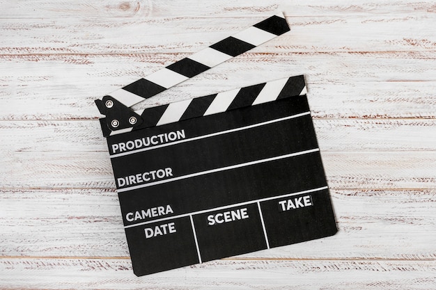 Free photo an elevated view on clapperboard over white wooden desk