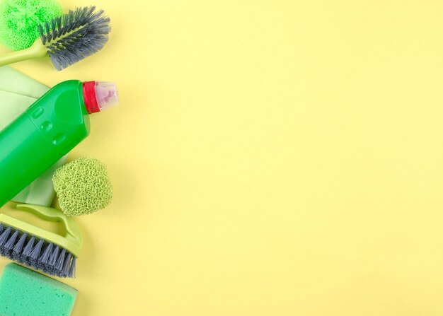 Elevated view of cleaning equipments on yellow background