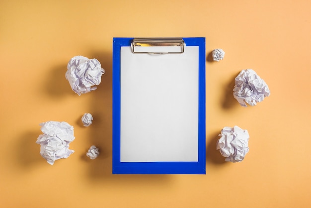 Elevated view of clipboard with blank paper surrounded by crumpled papers