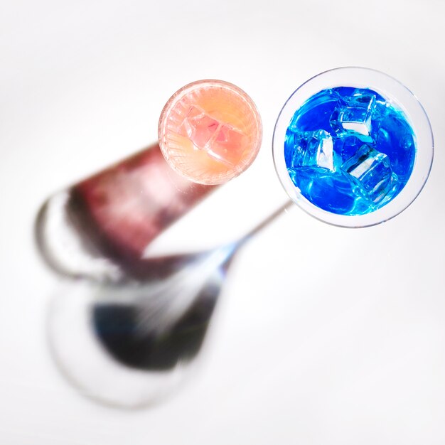 An elevated view of cocktail glasses with shadow on white background