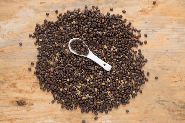 Elevated view of coffee beans with spoon on wooden table