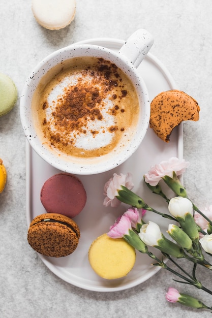 Free photo elevated view of coffee and macaroons with bunch of fresh flowers