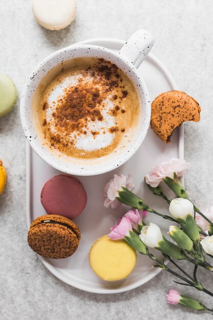 Elevated view of coffee and macaroons with bunch of fresh flowers