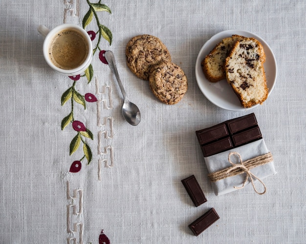 Elevated view of coffee with cookies, bread and chocolate