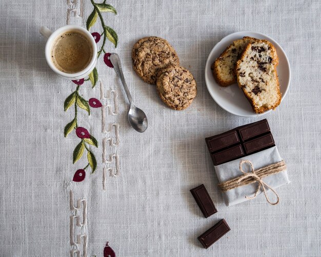 Elevated view of coffee with cookies, bread and chocolate