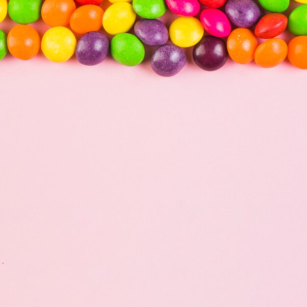 Повышенный вид красочных конфет в верхней части розового фона