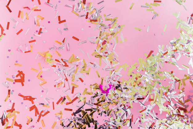 Elevated view of colorful confetti on pink background