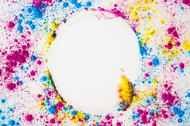 Elevated view of colorful face powder forming circular frame on white surface