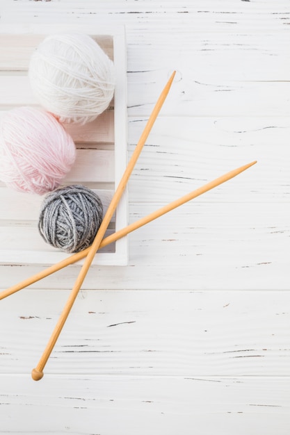 Free photo elevated view of colorful yarns and crochet on wooden background