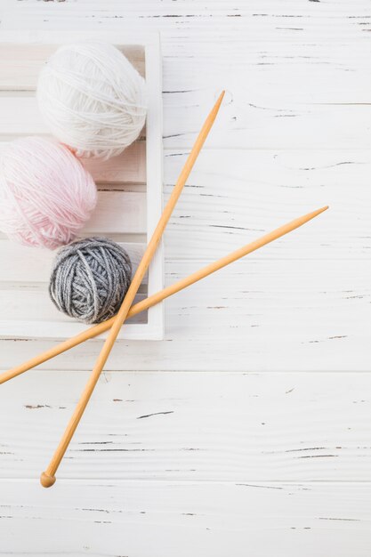 Elevated view of colorful yarns and crochet on wooden background