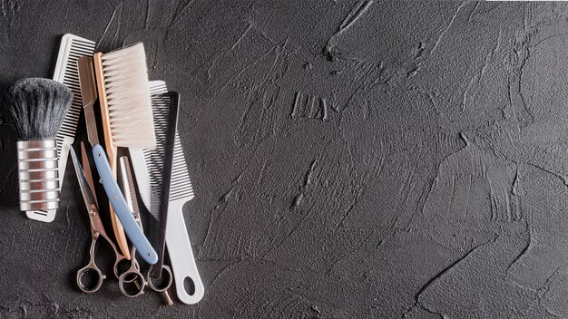 Elevated view of combs, scissors and razor on black surface