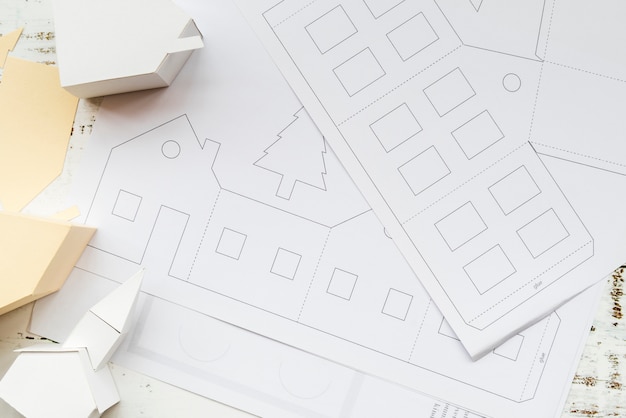 Поднятый вид творческой модели бумажного дома и белой бумаги на столе