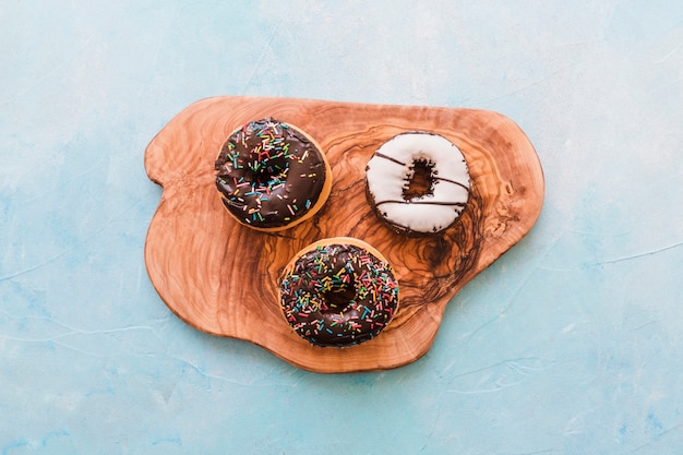 Elevated view of delicious donuts on wooden chopping board