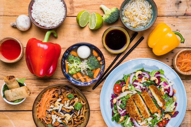 An elevated view of delicious thai food with fresh vegetables on wooden table