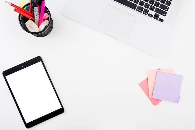 Elevated view of digital tablet; adhesive notes and laptop on white background