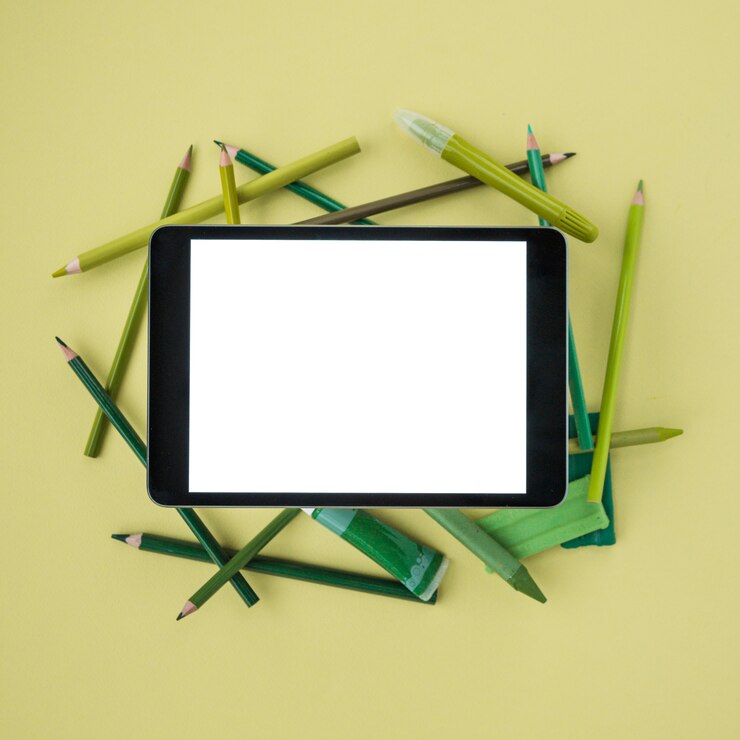 Free Photo elevated view of digital tablet with white screen on painting accessories over plain colored surface