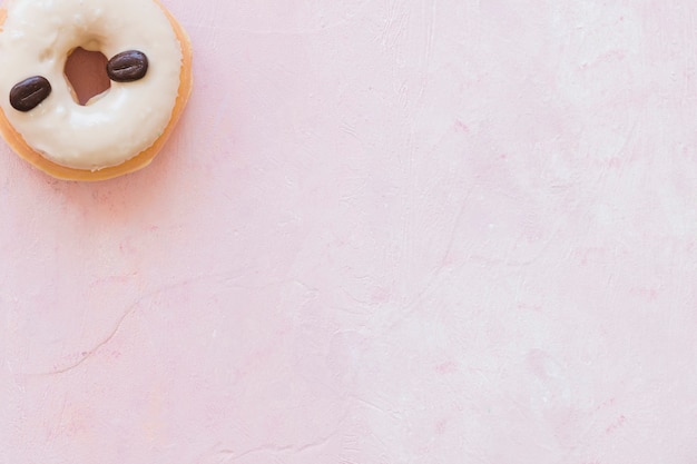 Elevated view of donut decorated with coffee beans on pink background