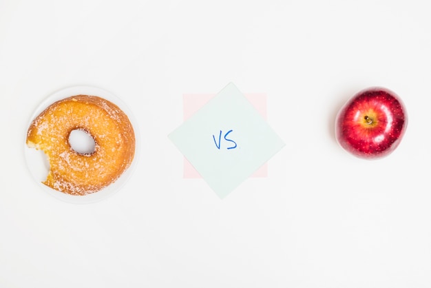 Elevated view of donut versus apple on white surface