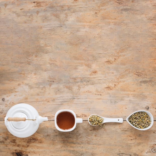 Elevated view of dried chinese chrysanthemum flowers; teapot and lemon tea arranged in a row on table