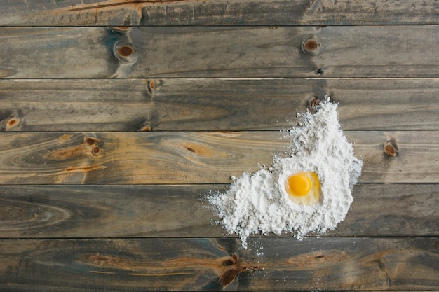 Free photo elevated view of egg and flour on wooden surface