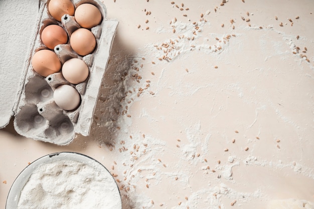 Free photo elevated view of eggs with flour in bowl on background