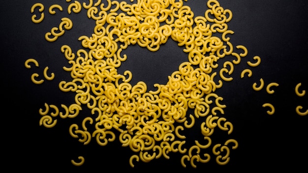 Free photo elevated view of elbow macaroni raw pasta on black surface