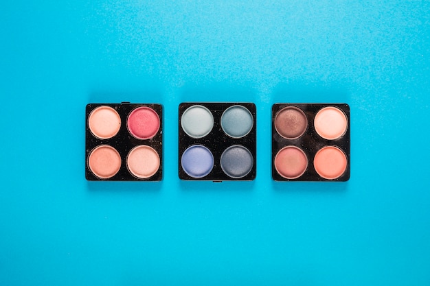 Elevated view of eye shadow powders on blue background