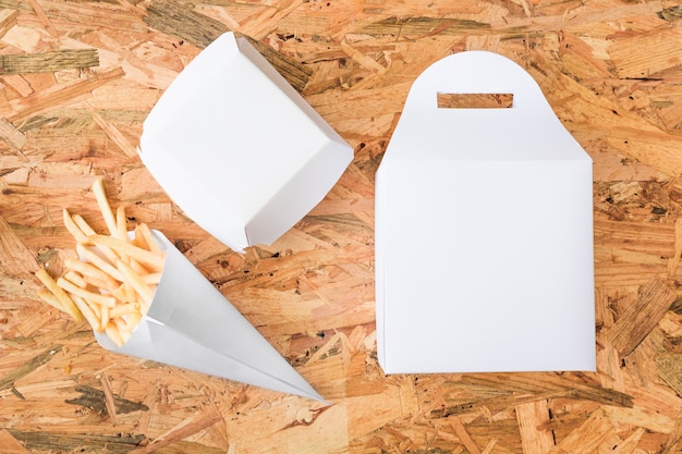 Elevated view of french fries and packages on wooden table