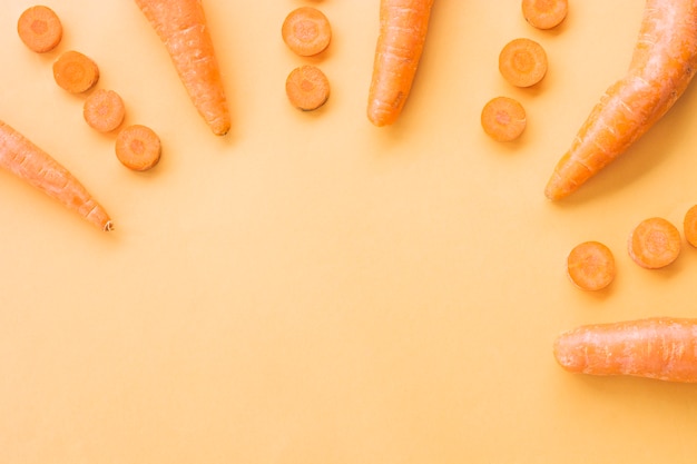 Elevated view of fresh carrots on orange backdrop