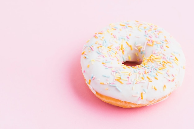 Elevated view of fresh decorative donut on pink background