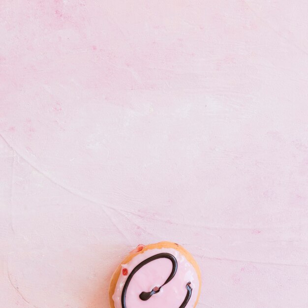 Elevated view of fresh donut at the bottom of pink background