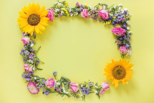 Free photo elevated view of fresh flowers forming frame on yellow surface