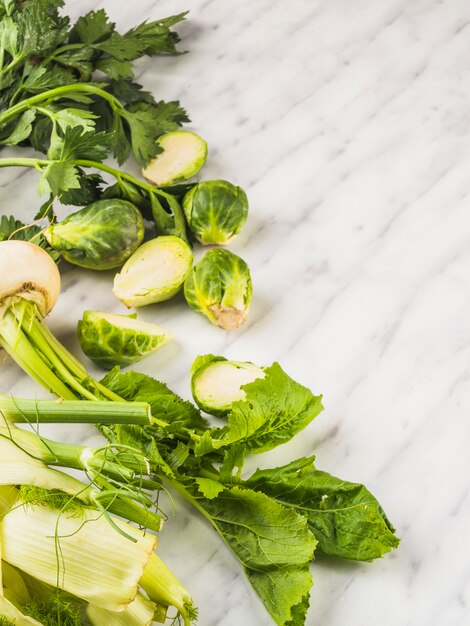 Elevated view of fresh green vegetables on marble background