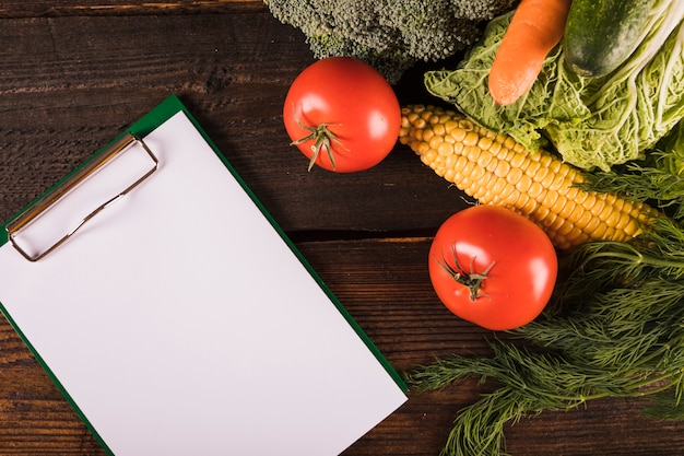 Elevated view of fresh healthy food with blank clipboard on wooden desk