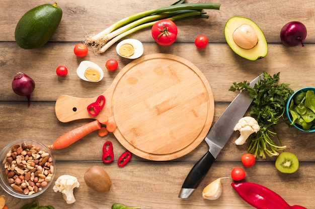 Elevated view of fresh ingredients; egg; vegetables and chopping board with knife on table