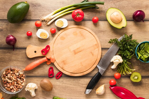 Elevated view of fresh ingredients; egg; vegetables and chopping board with knife on table